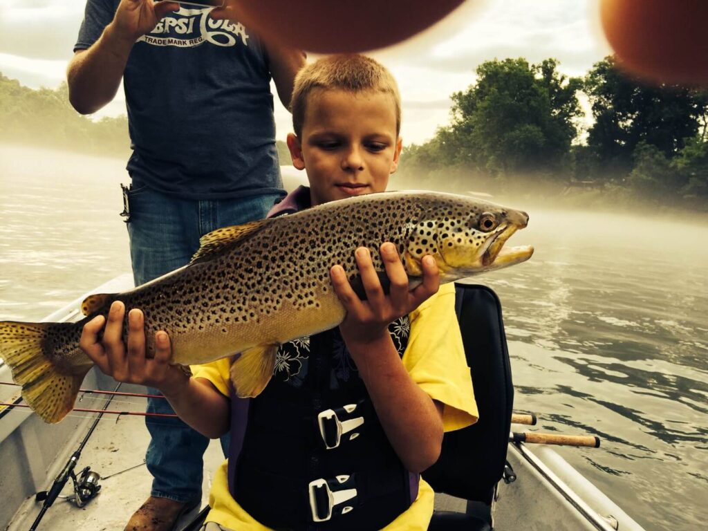 A Young boy holding a brown trout